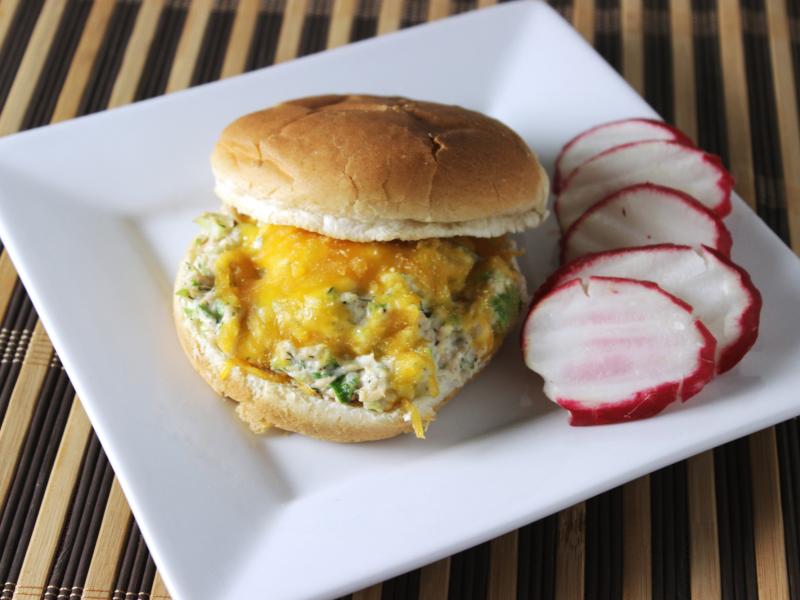 salmon salad on toasted bun with melted cheddar cheese with radish chips on side