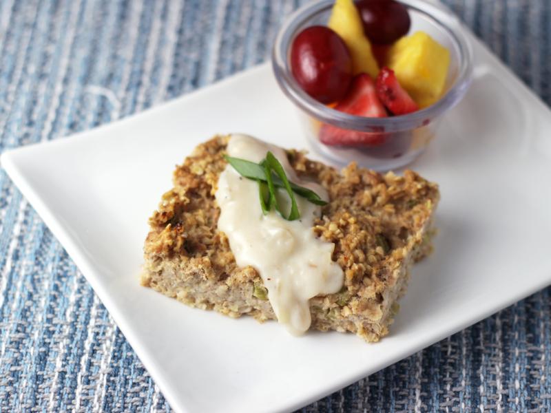 tuna casserole topped with white onion sauce with fruit salad on the side