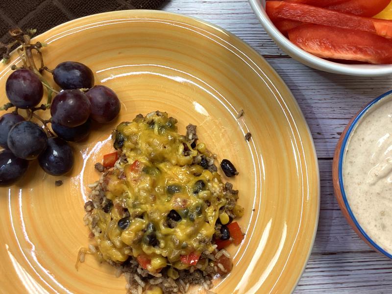 portion of skillet meal on yellow plate with grapes on the side