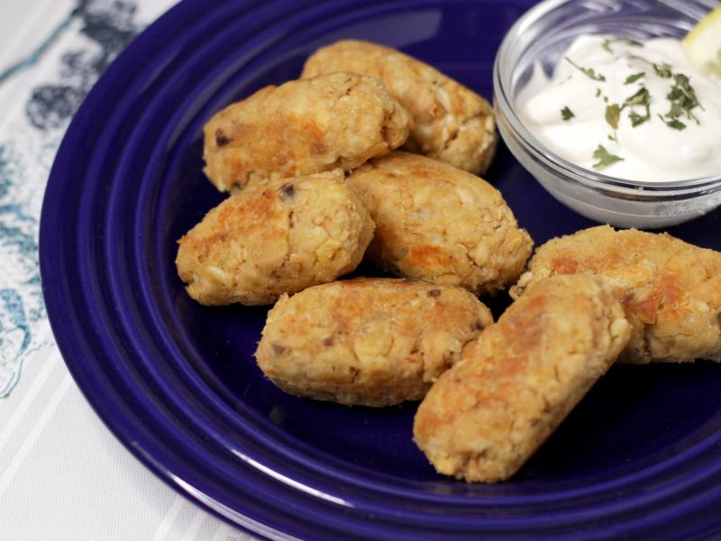 7 salmon tots on a blue plate with a small bowl of tartar sauce