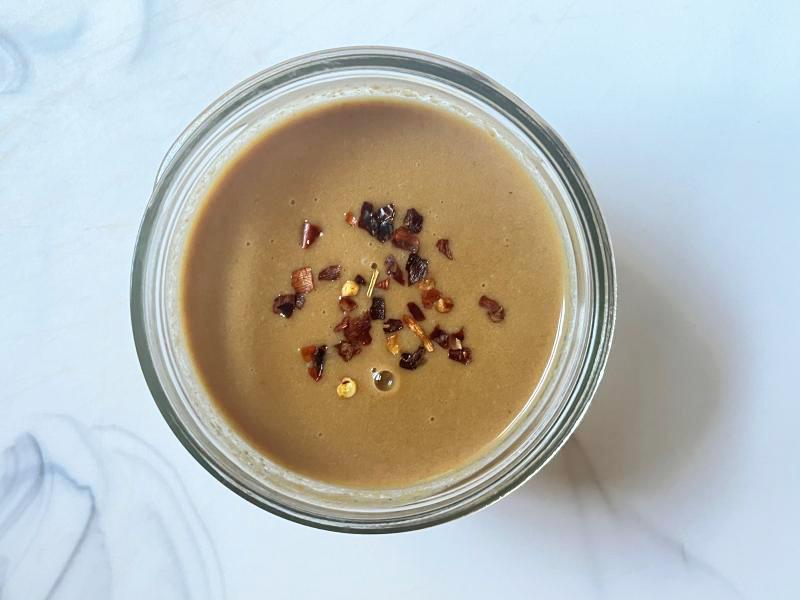 small bowl with peanut butter sauce topped with red pepper flakes