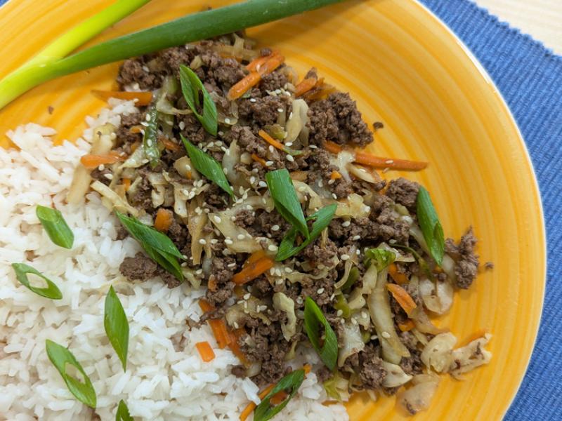 cooked ground venison with cabbage and carrots over white rice, topped with green onions