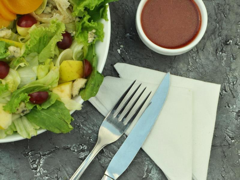 small cup of dressing next to a green salad