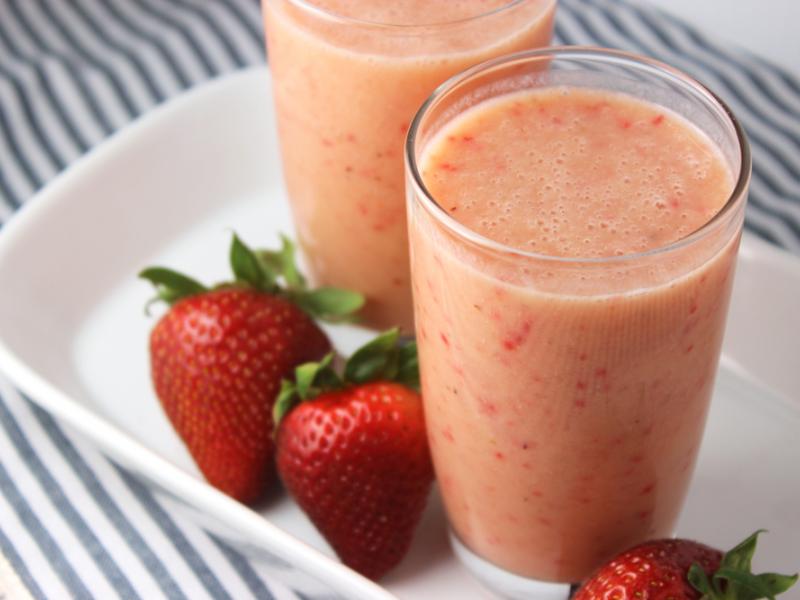 two glasses filled with Fruit and Yogurt Breakfast Smoothie with whole strabwerries on the side