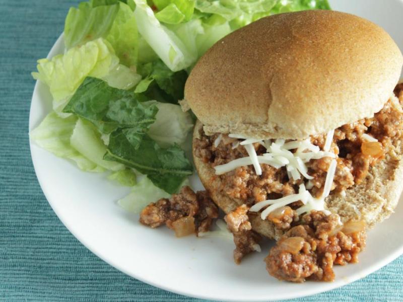 pizza bun sandwich on a white plate with side salad