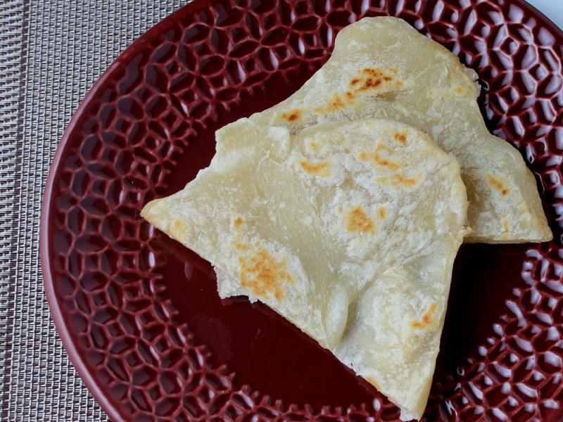 two pieces of Chapatis Flatbread on a maroon plate