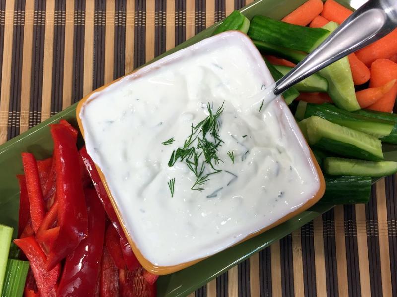 cucumber dill yogurt dip in a bowl next to raw vegetables