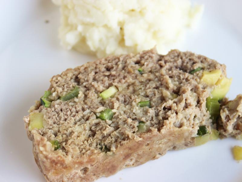 slice of turkey meatloaf on a white plate with a side of mashed potatoes