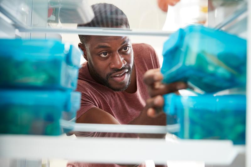 man reaching into fridge for leftovers