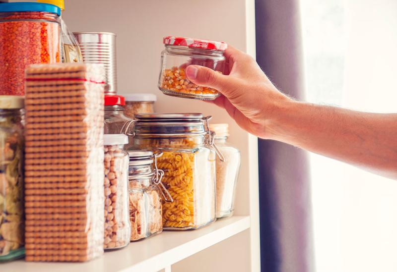 person reaching into pantry for a jar of dried corn