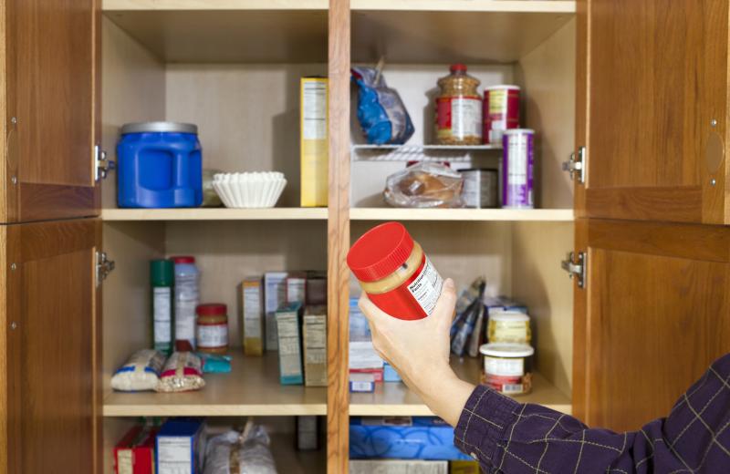 person reaching into a pantry for a jar of peanut butter